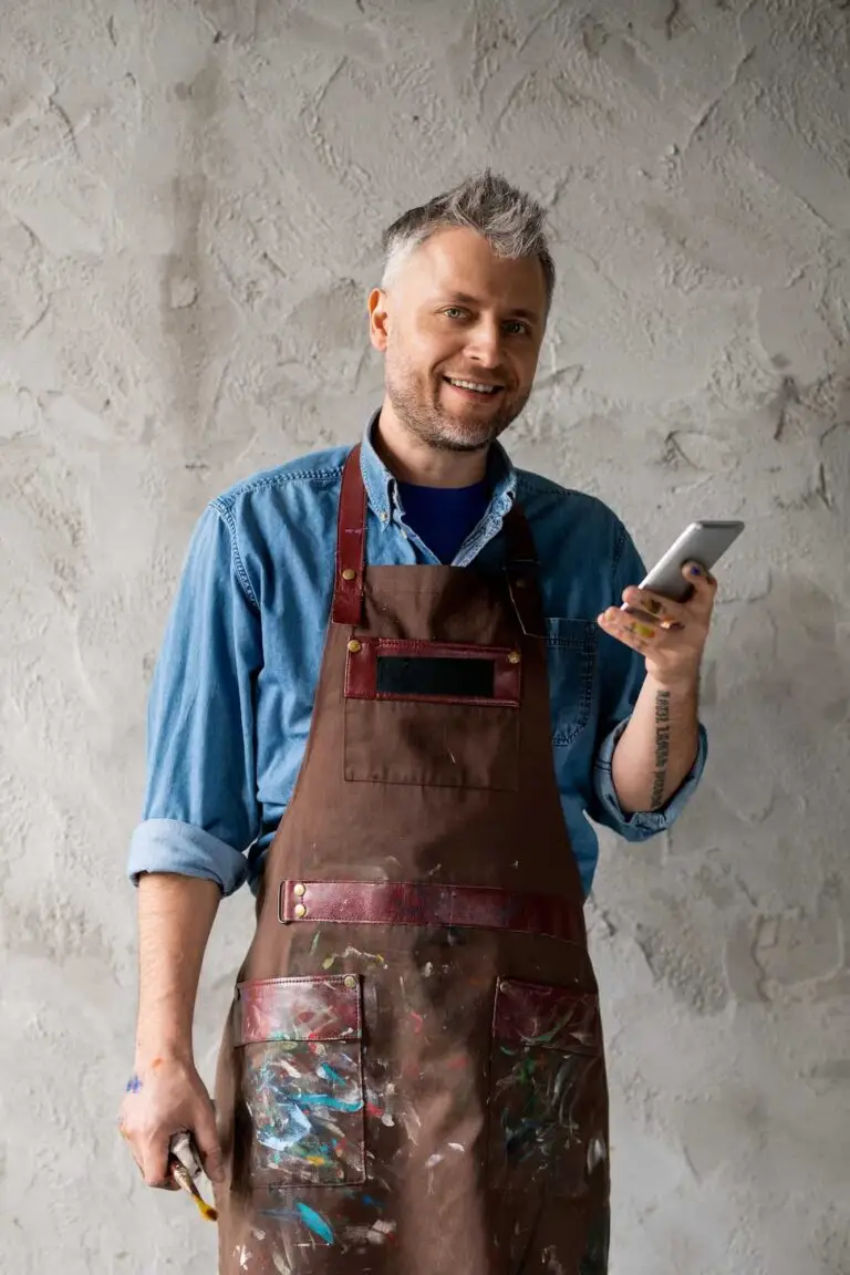 Professional painter holding a paintbrush and smartphone – what to know before hiring a painter in Carmel, Indiana