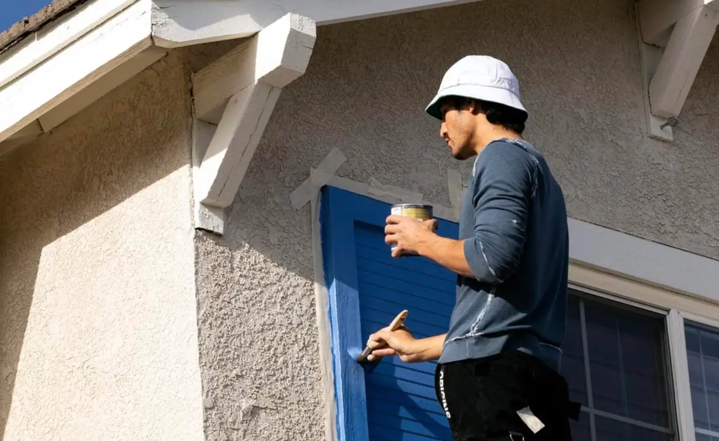 Professional painter repainting a window shutter on a house exterior