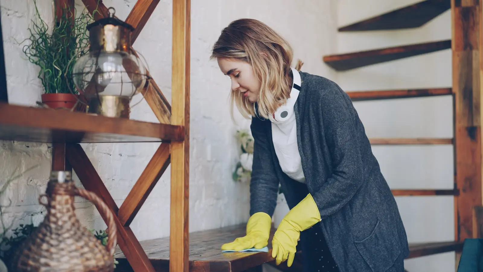 Homeowner wearing gloves cleaning a painted interior wall as part of routine paint care and maintenance