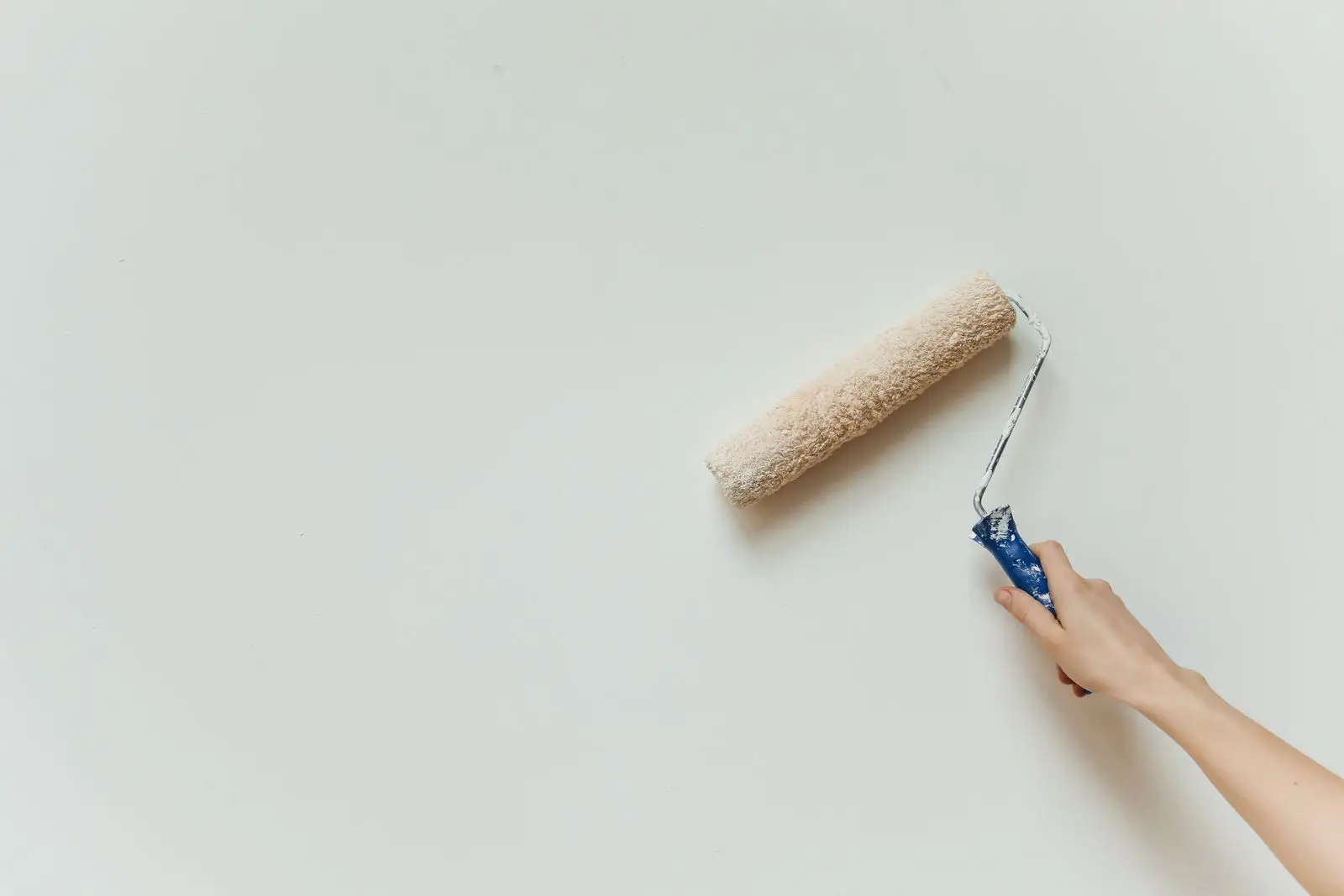 Roller applying the first coat of wall paint on day two of an interior painting timeline