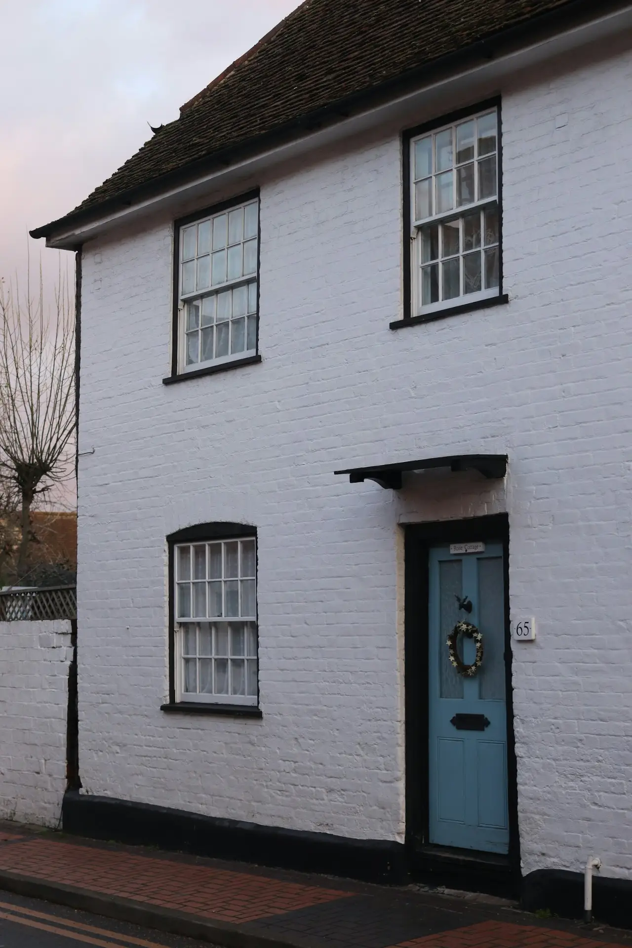 Soft white limewashed brick facade with a black front door — European limewash style