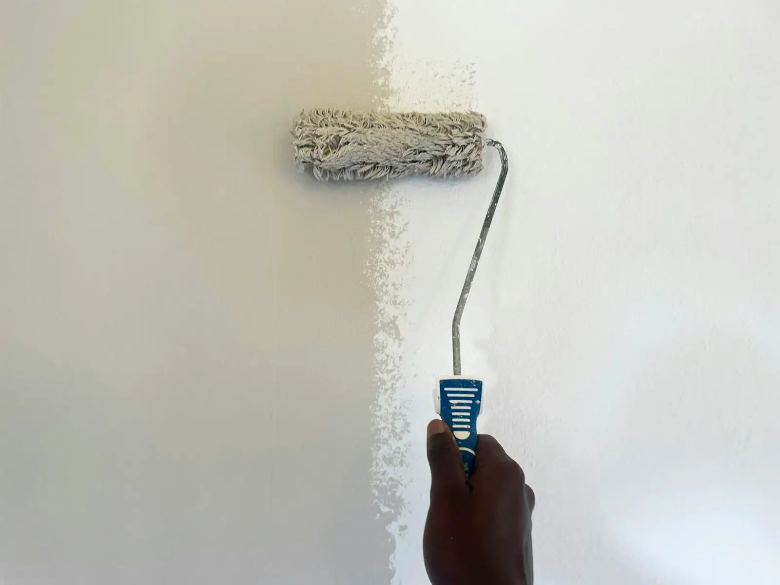 Using a small roller to blend a paint touch-up on an interior wall