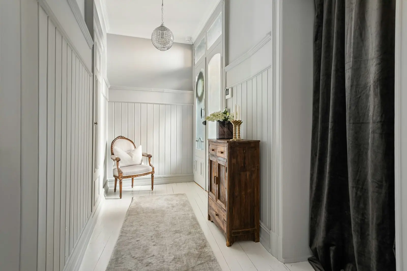 Hallway with white painted trim, wainscoting and baseboards in excellent condition