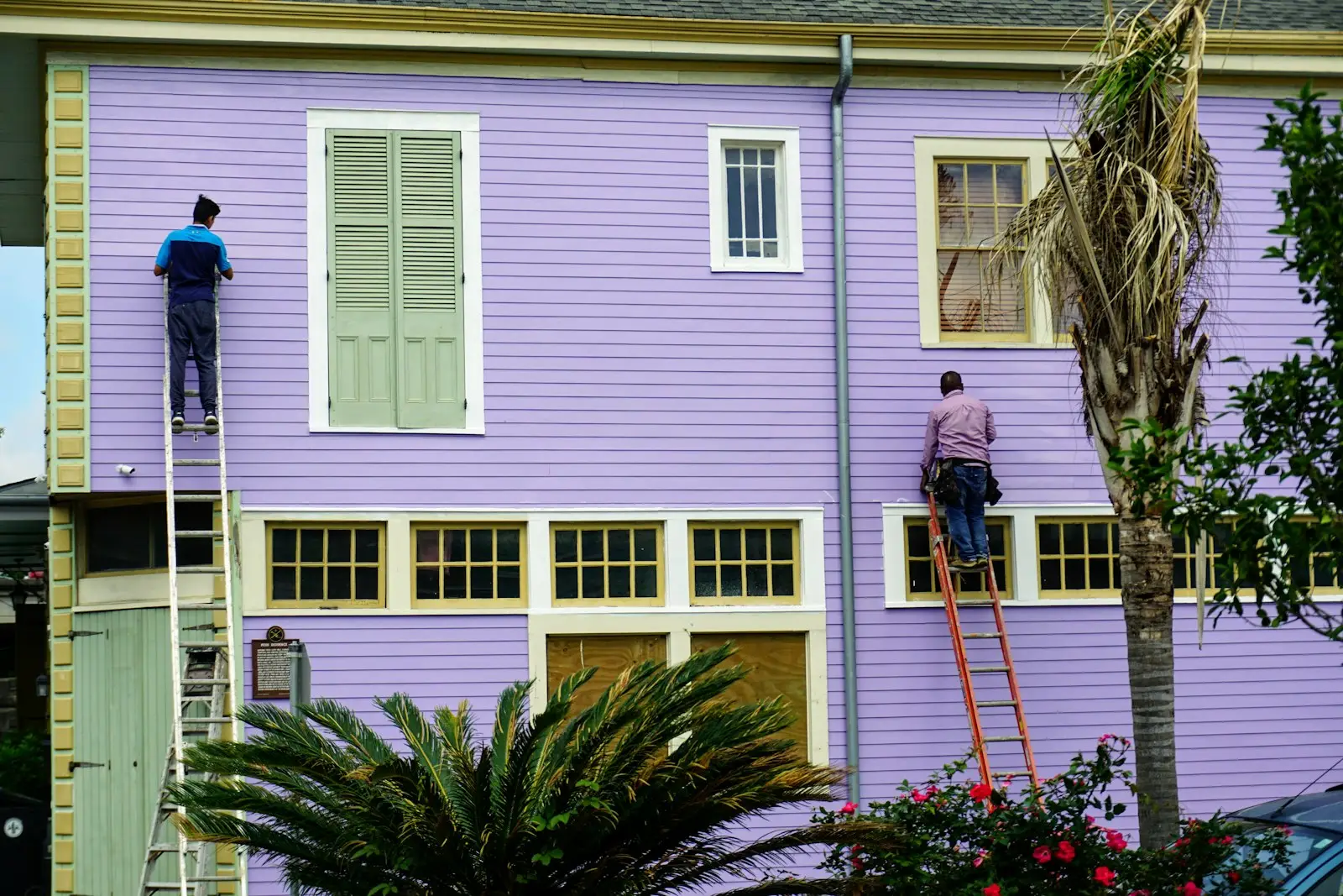 Professional painters on ladders repainting the exterior of a house